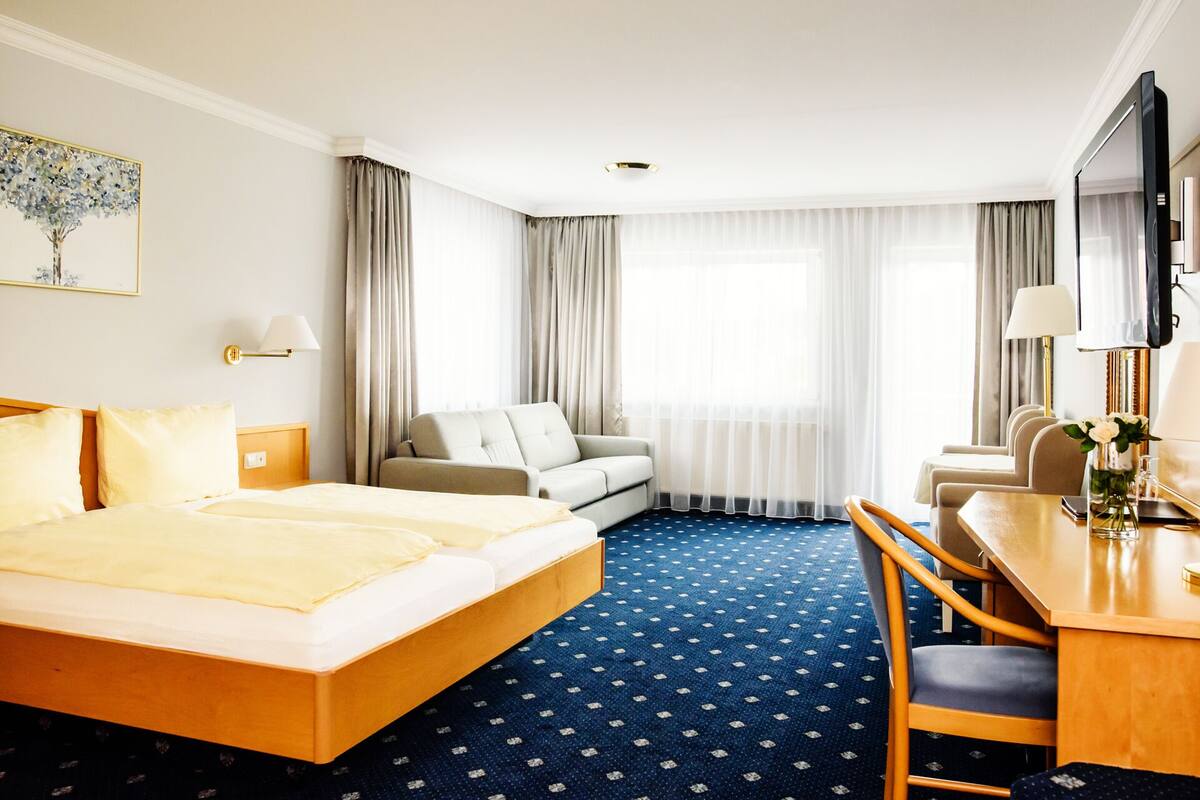 Een hotelkamer met een bed, een bank, een bureau en een televisie.