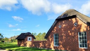 A brick building with a thatched roof, a small window, and a door.