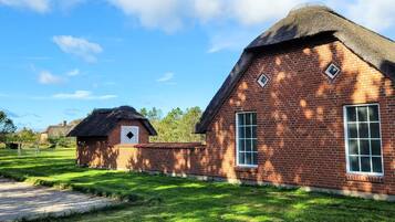 A brick building with a thatched roof, a small window, and a door.