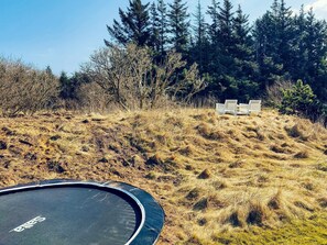 A trampoline on a grassy hill with a bench in the background. - 5 Star Holiday Home in Ulfborg (Ulfborg)