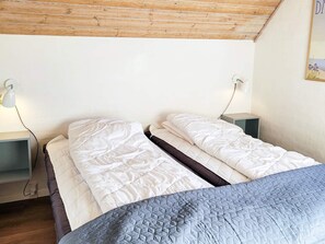 A bedroom with two beds, wooden ceiling, bedside tables, and a wall-mounted lamp. - 5 Star Holiday Home in Ulfborg (Ulfborg)