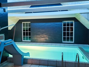 An indoor swimming pool with a dark wall and two windows. - 5 Star Holiday Home in Ulfborg (Ulfborg)