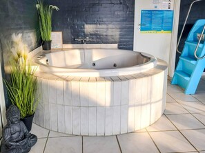 A spa area with a hot tub, a Buddha statue, and a potted plant. - 5 Star Holiday Home in Ulfborg (Ulfborg)