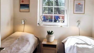 A bedroom with two beds, a window with a view of the outside, and wall-mounted artwork.