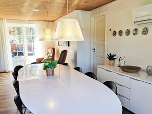 Uma sala de jantar moderna com uma mesa grande, cadeiras e iluminação pendente.