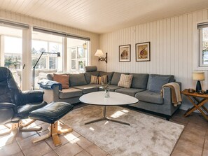 A cozy living room with a sectional sofa, a round coffee table, and a black leather chair.