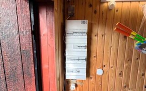 A wooden wall with a whiteboard and a red door.