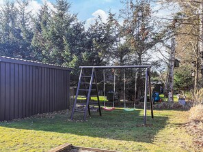 Un patio trasero con un columpio, una escalera y una zona cercada.