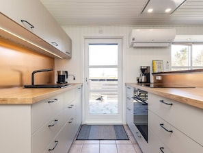 A modern kitchen with white cabinetry, black handles, and a coffee maker on the countertop. - 5 Star Holiday Home in Hals (Hals)
