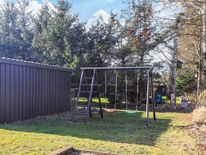 A backyard with a swing set, a wooden ladder, and a shed. - 5 Star Holiday Home in Hals (Hals)