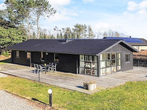 A modern building with a flat roof, large windows, and a wooden deck.
