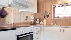 A kitchen with wooden panel walls, a built-in oven, a coffee maker, and a window with a view. - Seaside Escape in Snogebaek - By Traum Ferienwohnungen (Nexø)