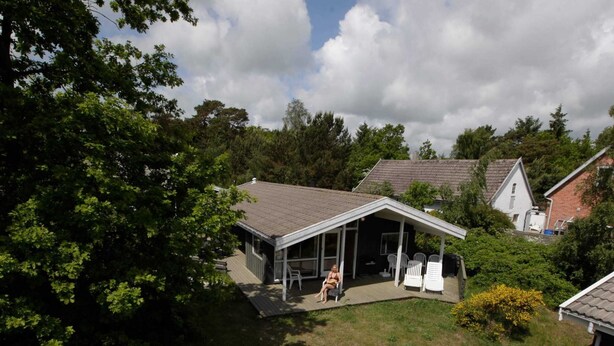 A house with a covered patio, a lawn, and a neighboring building. - Seaside Escape in Snogebaek - By Traum Ferienwohnungen (Nexø)