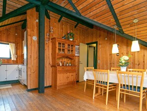A wooden interior with a dining area, wooden cabinets, and a ceiling with exposed beams.