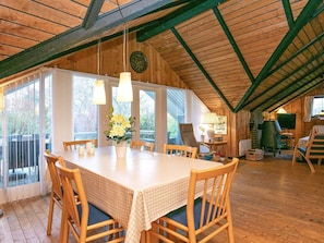 A dining area with a table set for four, wooden chairs, a vase with flowers, and a large window.