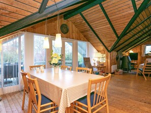 A dining area with a table set for four, wooden chairs, a vase of flowers, and a large window providing natural light.