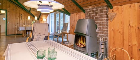 A cozy room with a fireplace, a dining table with chairs, and a hanging light fixture.