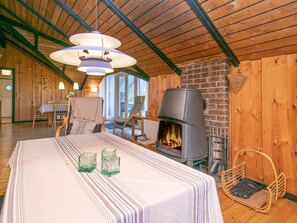 A cozy room with a fireplace, a dining table with chairs, and a hanging light fixture.
