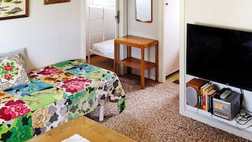 Un dormitorio con una cama, una mesita de noche, un televisor y una estantería.