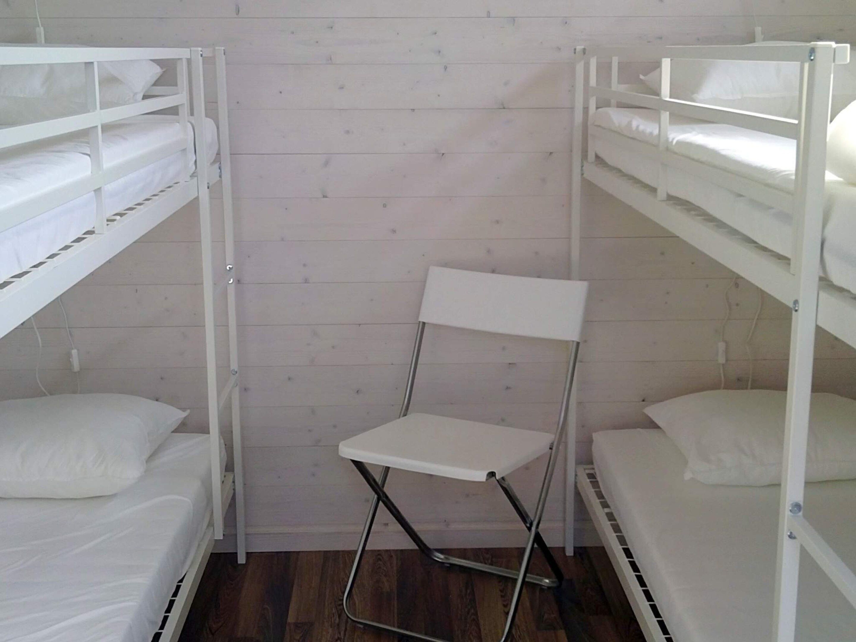 Habitación con literas y una silla plegable en el centro.