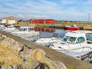 A marina with boats docked, a red building, and a wooden dock.
