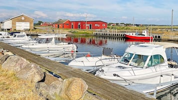 A marina with several boats docked, a red building in the background, and a wooden dock in the foreground.