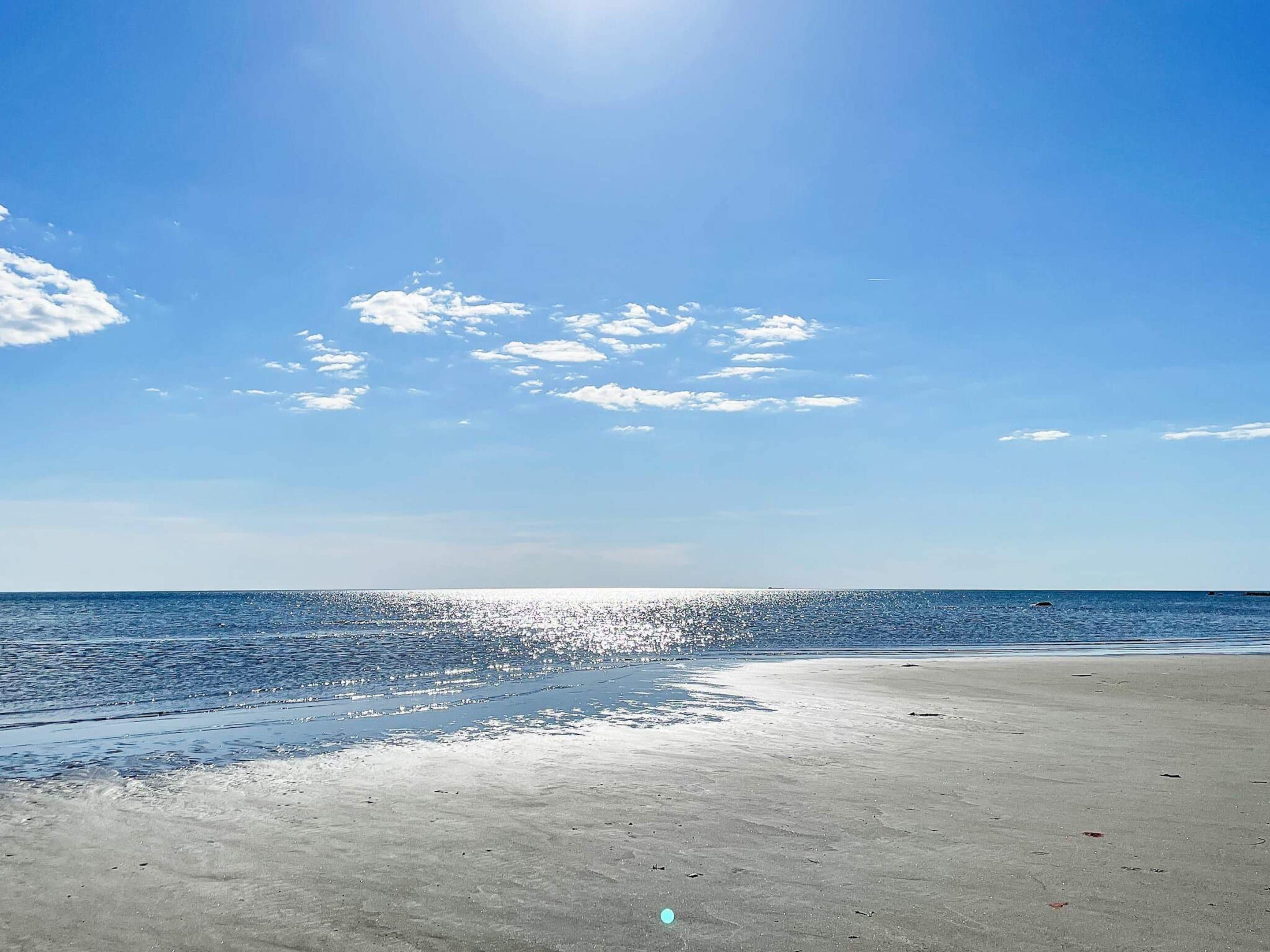 Una playa con cielo despejado y mar tranquilo.