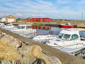 A marina with boats docked, a red building, and a wooden dock. - 8 Person Holiday Home in Tvaaker (Tvaaker)