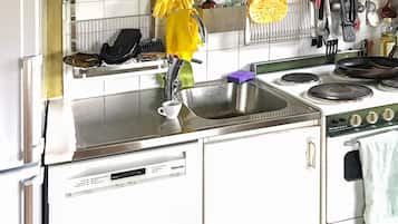 Una cocina con un fregadero, estufa y diversos utensilios colgados.