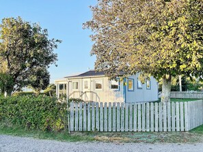 A single-story house with a wooden fence, surrounded by trees and a clear sky. - 8 Person Holiday Home in Tvaaker (Tvaaker)