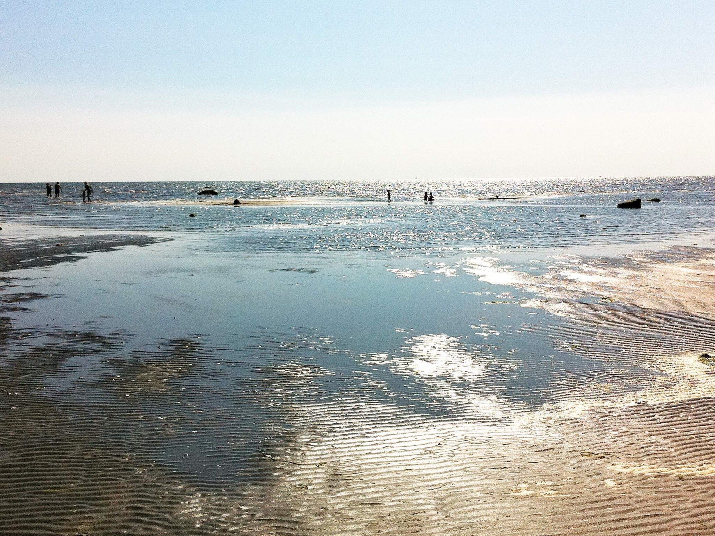 A beach with clear water and a sandy shore.