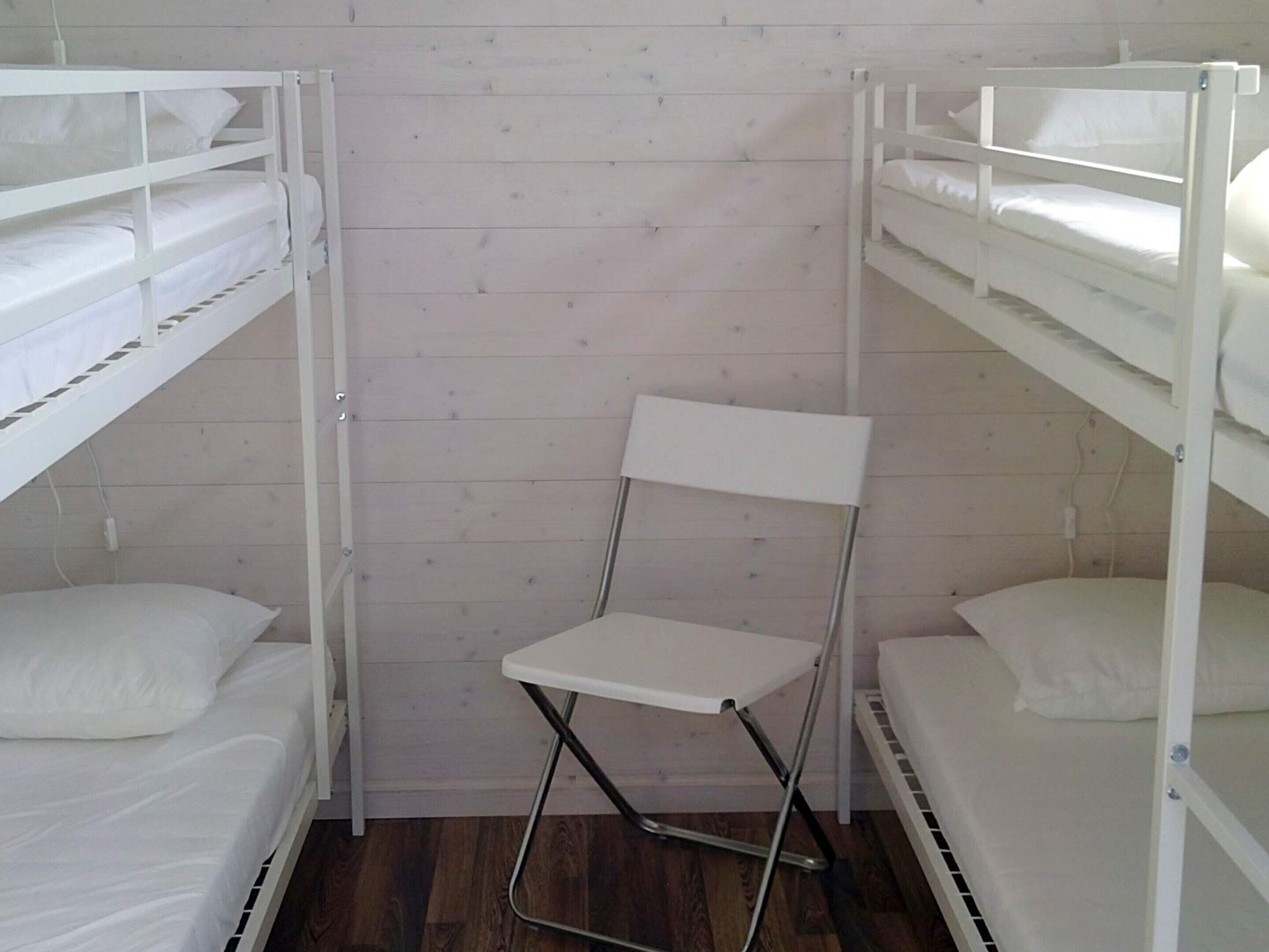 A bunk bed room with a foldable chair in the center.