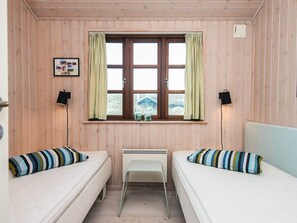 A room with two beds, a window with curtains, a radiator, and a picture on the wall. - 4 Star Holiday Home in Hvide Sande (Hvide Sande)