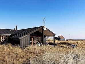 A wooden building with a sloped roof, a satellite dish, and a visible chimney.
