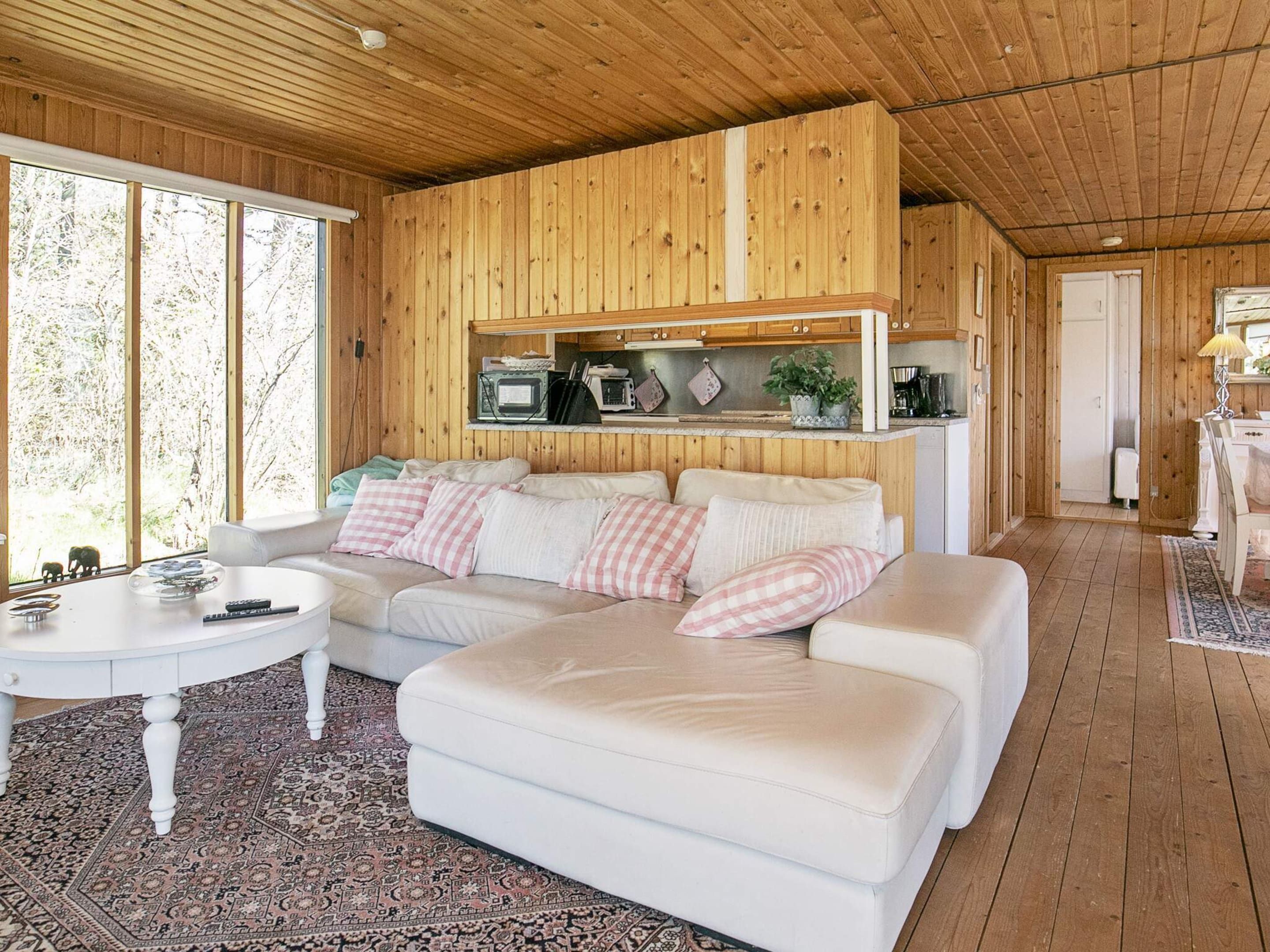 A cozy living room with a white sofa, a small round table, and a wooden ceiling.