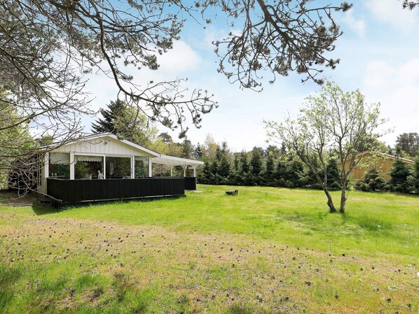 A house with a covered porch, a grassy yard, and a tree in the foreground.