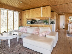 A cozy living room with a white sofa, a small round table, and a wooden ceiling.