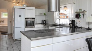 A modern kitchen with white cabinetry, stainless steel appliances, and a large island.