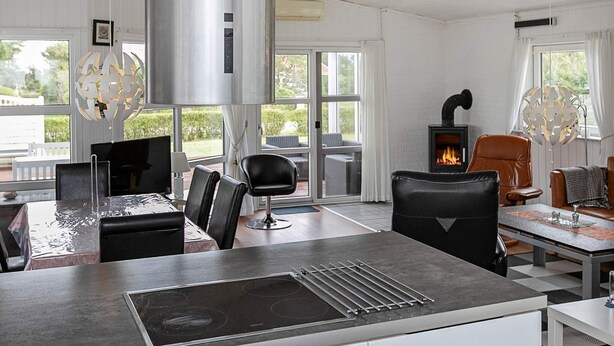 A modern kitchen with a central island, a built-in stove, and a dining area with a view of the outdoors.