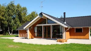 A modern building with a sloped roof, large windows, and a chimney. - 5 Star Holiday Home in Ulfborg (Ulfborg)
