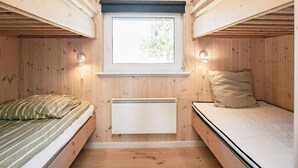 A compact room with bunk beds, a window, and a wall-mounted heater.