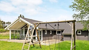 A house with a covered porch, a swing set, and a bicycle parked outside.