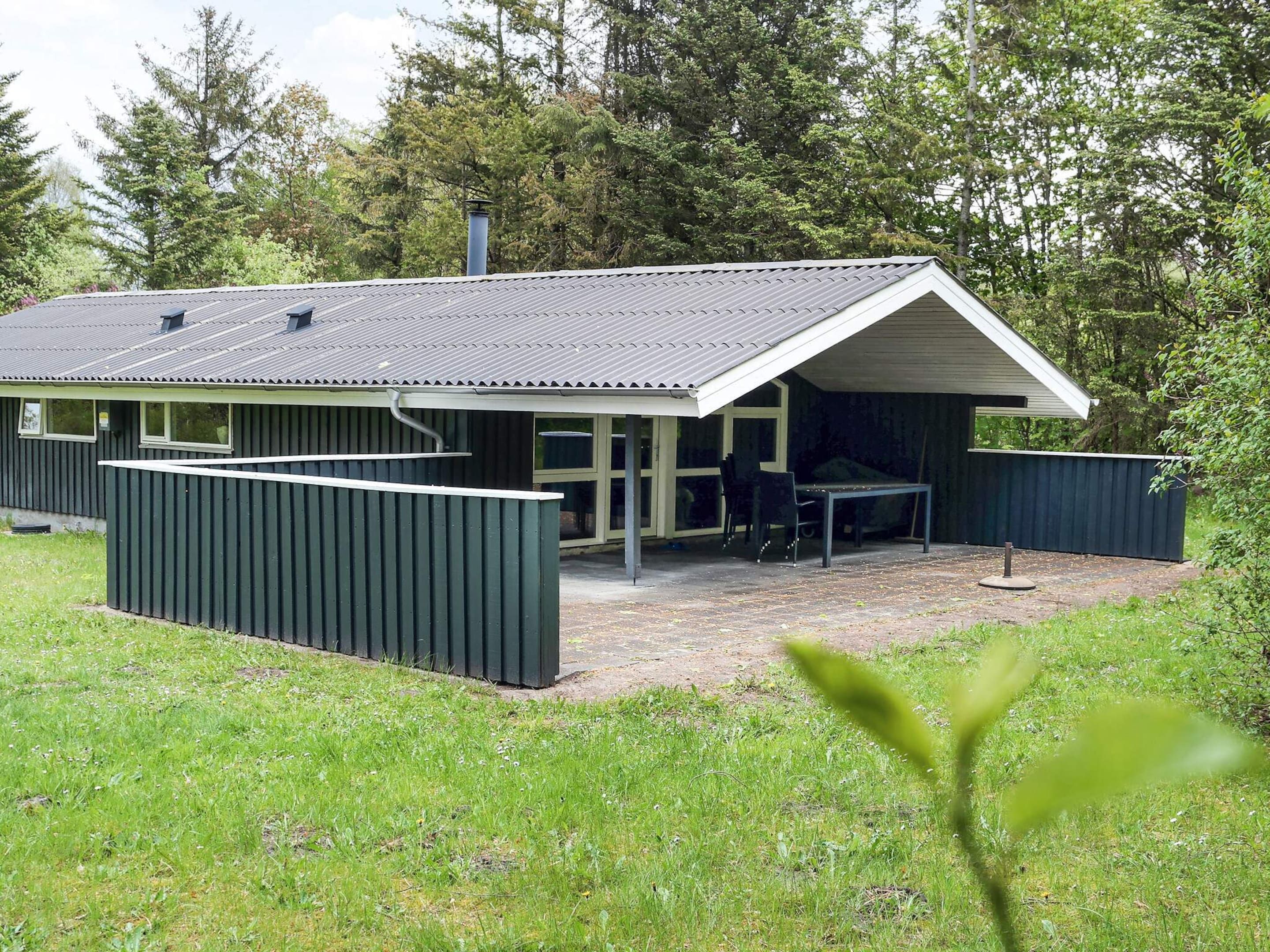 A single-story building with a covered patio area, a chimney, and a fenced outdoor space.