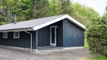 Un petit bâtiment de couleur sombre, doté d’un toit en pente, d’une porte et d’un petit porche.