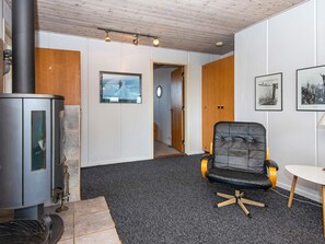A room with a fireplace, a black leather chair, and framed pictures on the wall. - 6 Person Holiday Home in Hvide Sande (Hvide Sande)