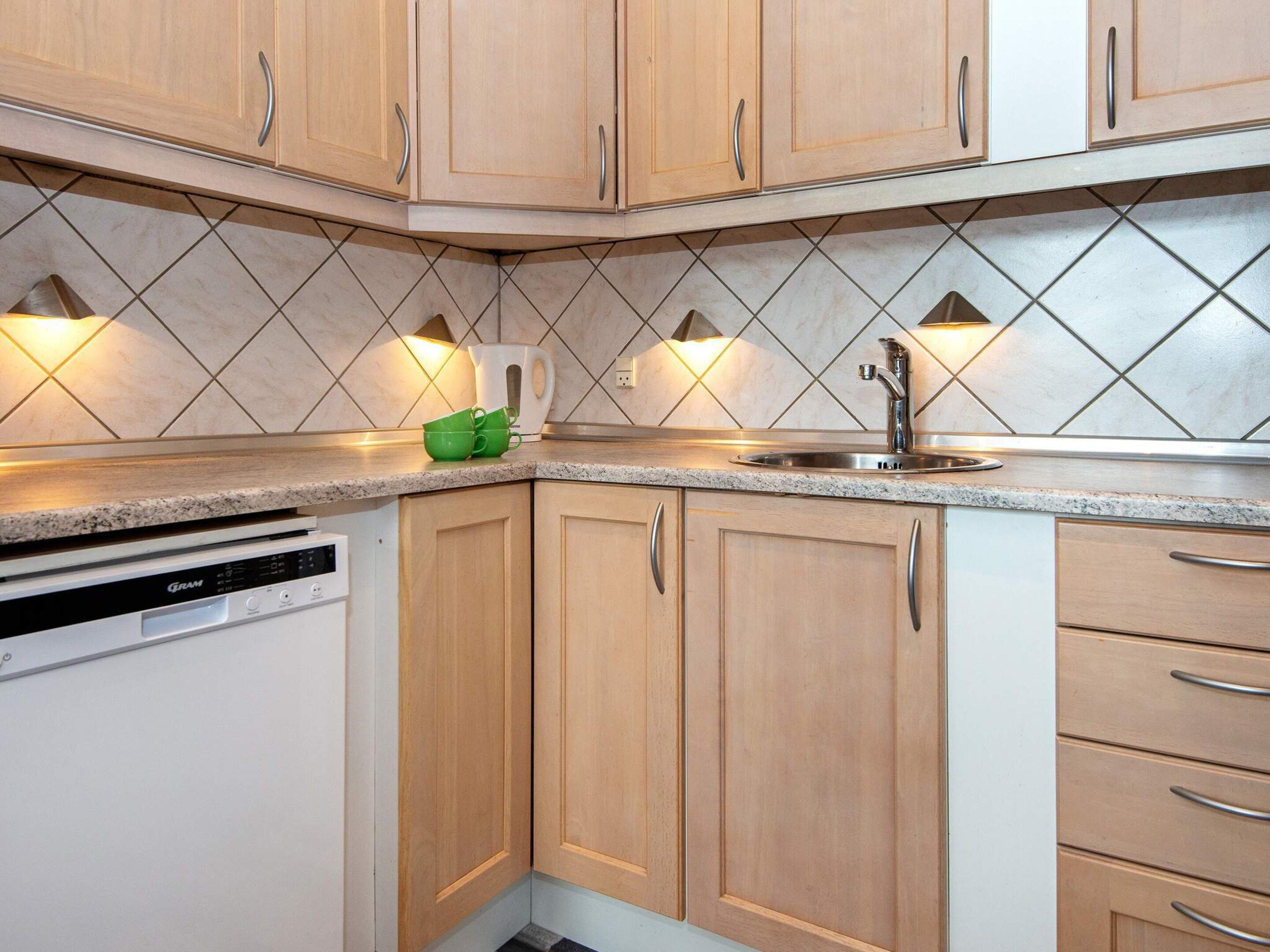 A kitchen with wooden cabinets, a stainless steel sink, and a dishwasher.