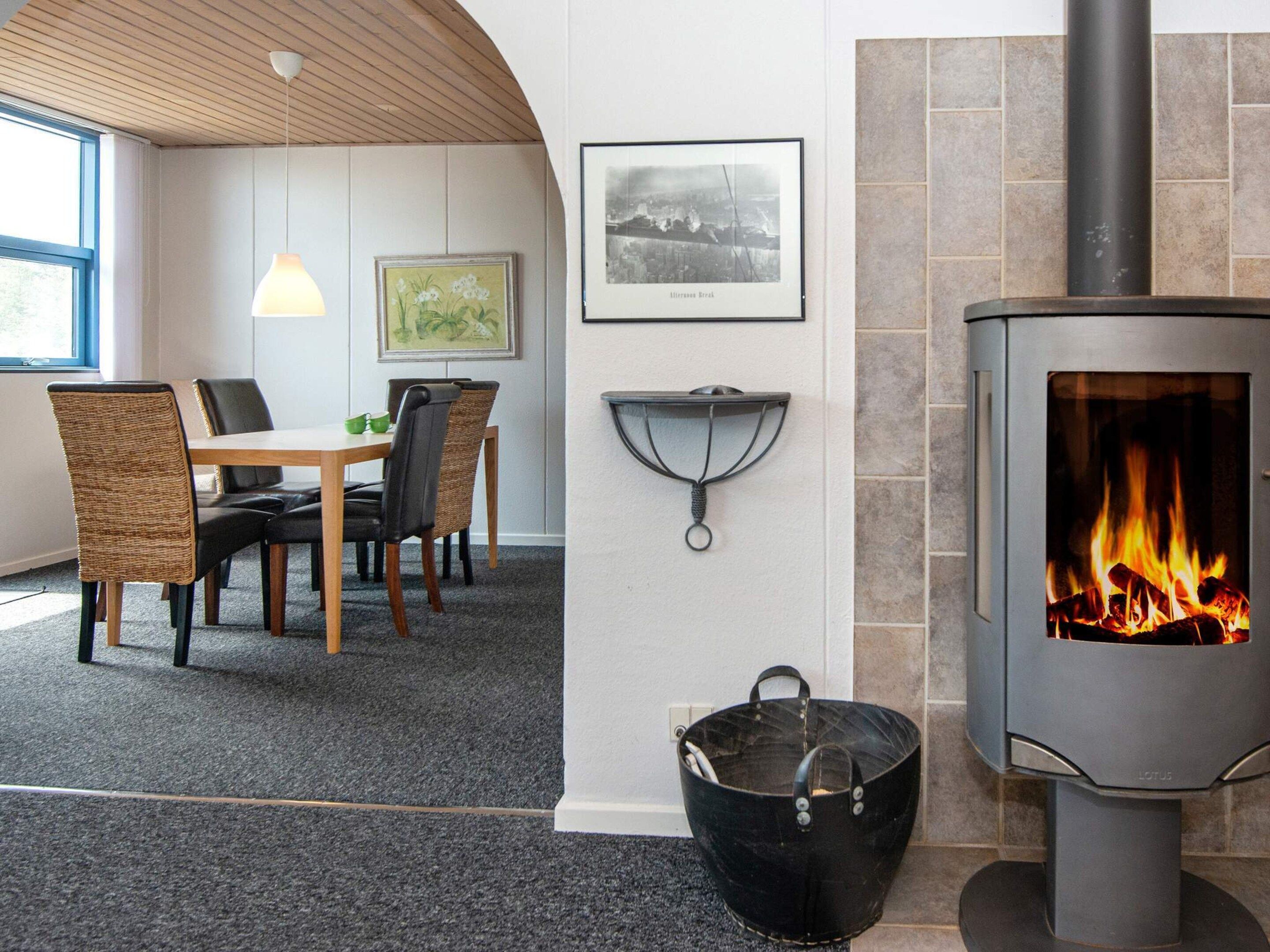 Una habitación con una mesa, sillas, una chimenea, un cuadro enmarcado y una lámpara colgante.