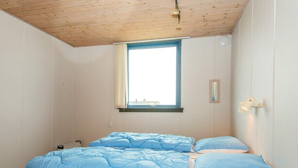 A room with a bed, a window, and a wall-mounted light fixture. - 6 Person Holiday Home in Hvide Sande (Hvide Sande)
