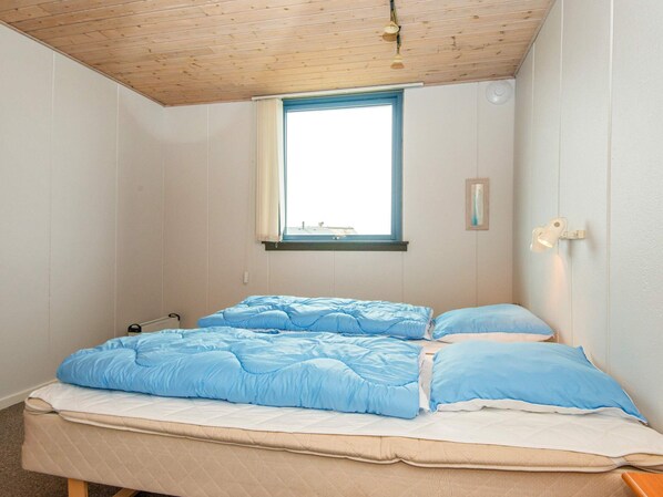 A room with a bed, a window, and a wall-mounted light fixture.