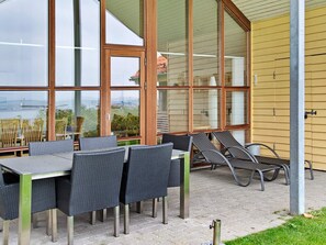 An outdoor patio with wicker furniture, large windows, and a view of a body of water. - 4 Star Holiday Home in Egernsund (Broager)